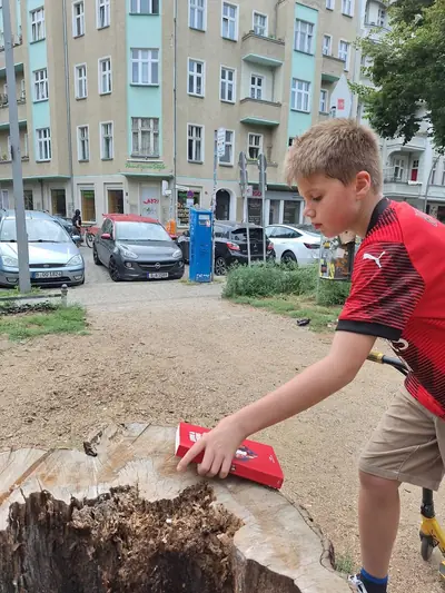 Een jongen op een step legt het boek op een boomstronk in een Berlijnse straat.